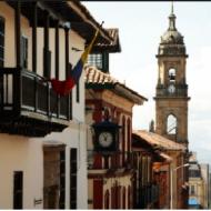 Conjunto de casas de uno y dos pisos con teja de barro y fachadas en pañete y pintura con remate en la torre de la Catedral Primada de Colombia, en el Centro Histórico de La Candelaria
