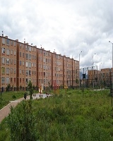 Imagen de un parque con una amplia zona verde alrededor y al lado derecho un conjunto de apartamentos. 