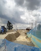 Imagen: De lado izquierdo a derecho se evidencia la realización de obras que se adelantan en los terrenos del plan parcial, en ellas se muestra una volqueta para luego continuar con montañas de arena y gravilla posteriormente se encierra con una malla azul para evitar el paso peatonal 