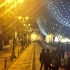 Peatones en calle del parque de Usaquén, con alumbrado nocturno