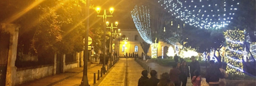 Peatones en calle del parque de Usaquén, con alumbrado nocturno