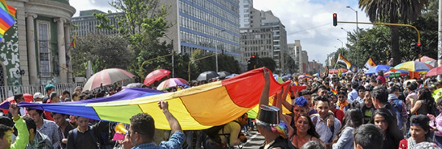 Personas marchando con una bandera LGBTI por la carrera 7a